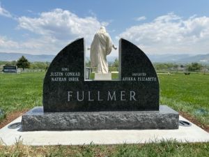 A granite tombstone with a statue of Jesus, names are listed on the sides and a large Fullmer at the bottom.