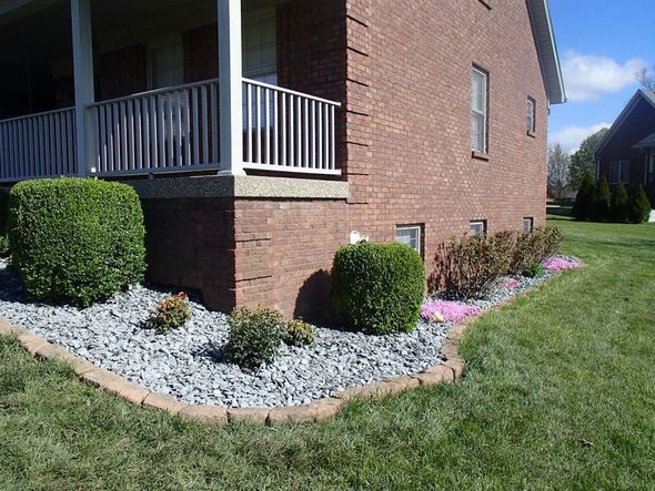 Brick house with green shrubs, gray gravel, and a border of brown bricks.