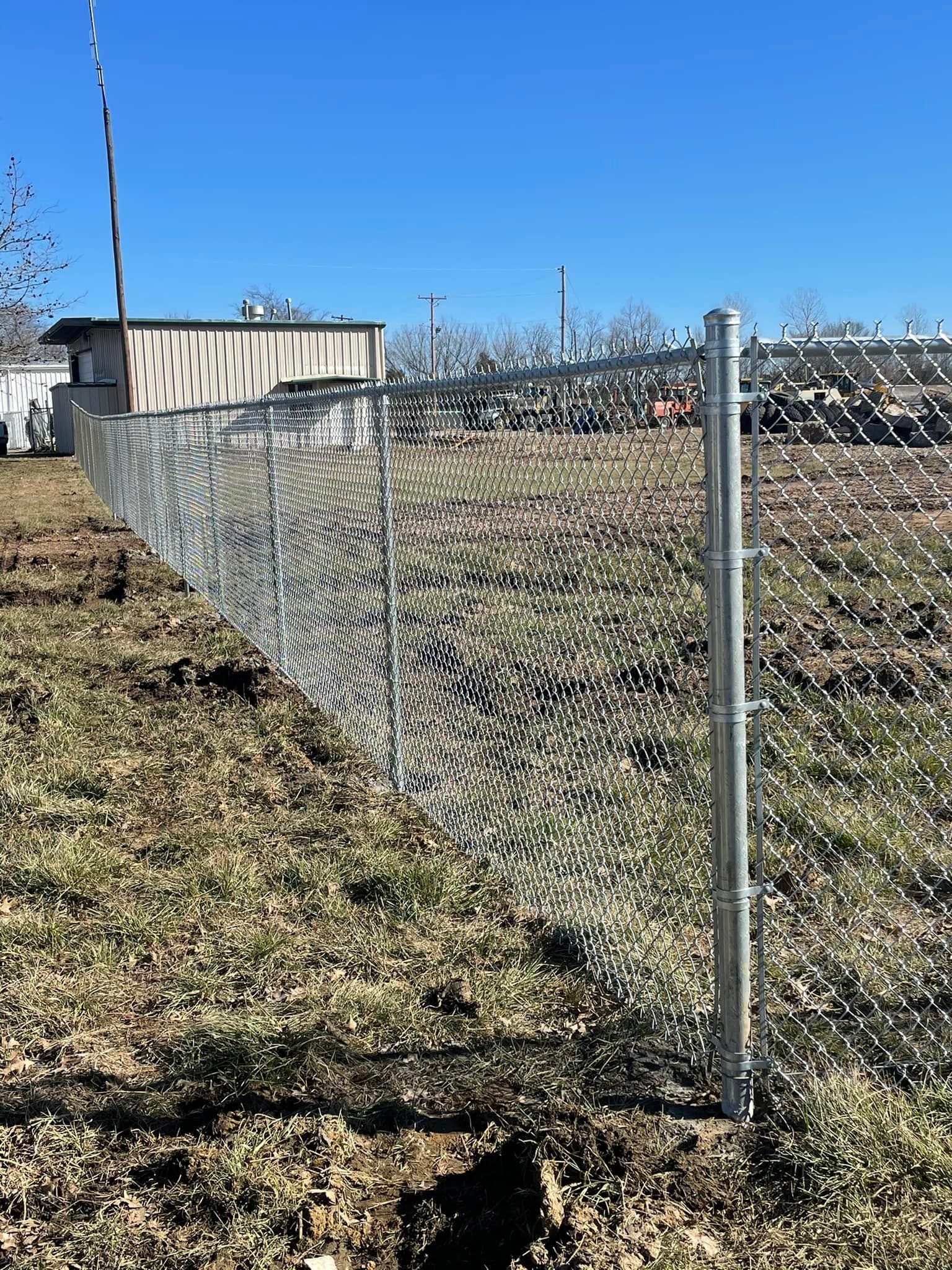 A chain link fence is sitting in the middle of a grassy field.