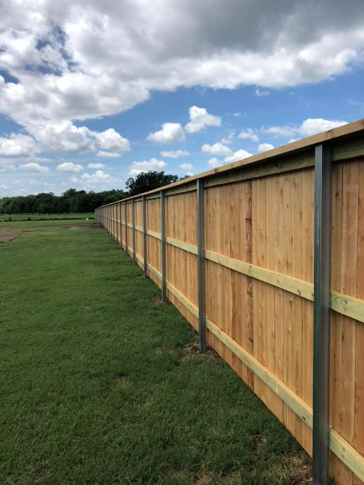 A wooden fence is sitting on top of a lush green field.