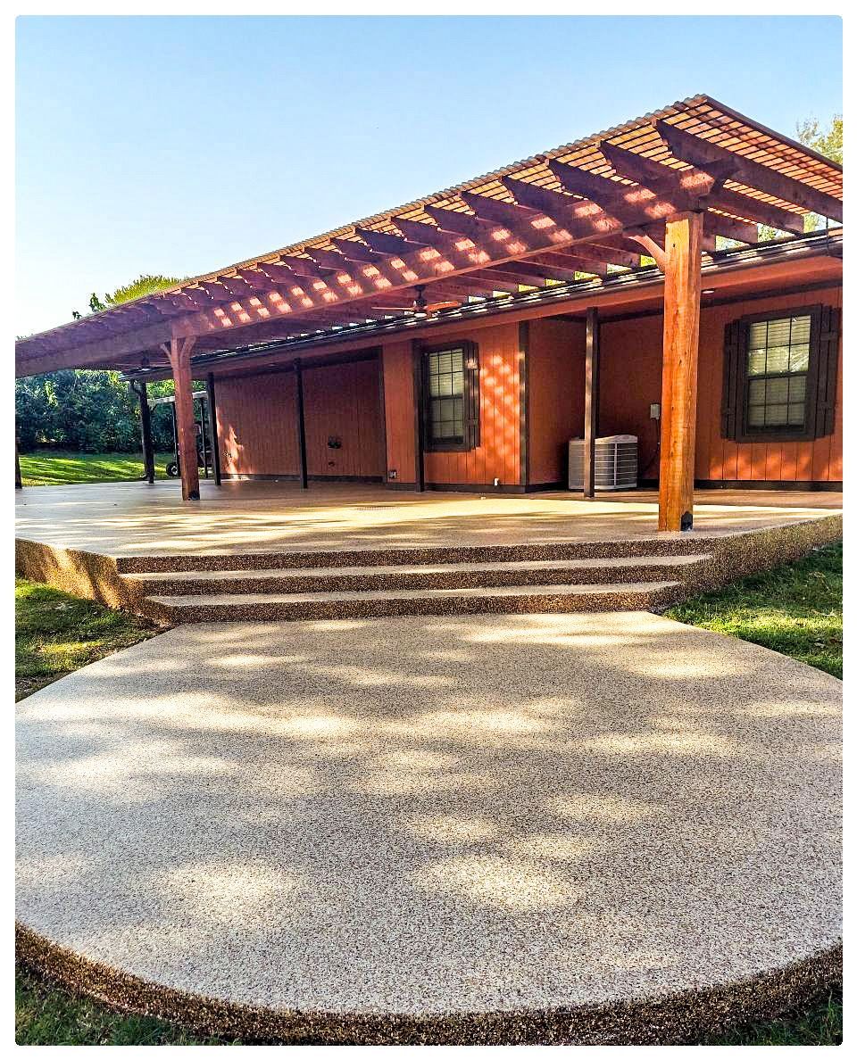 A house with a pergola on top of it and a concrete walkway leading to it