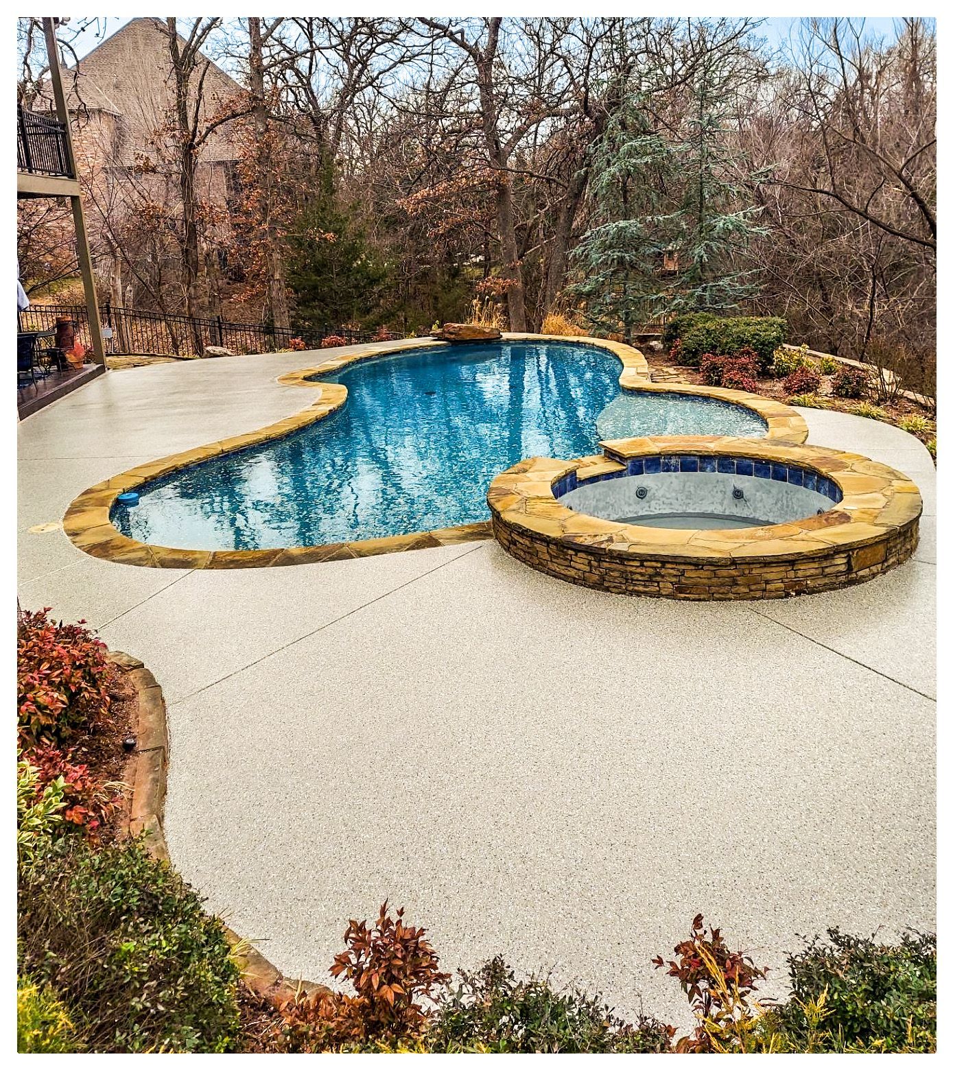 A large swimming pool with a hot tub in the backyard