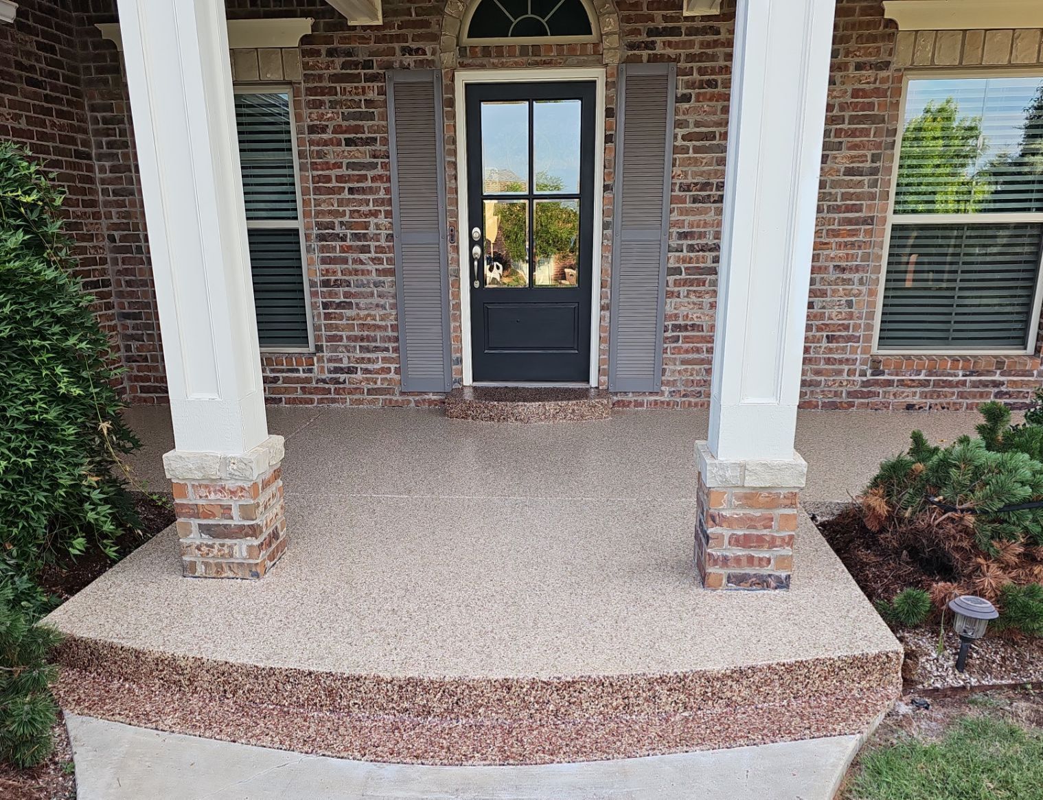 A brick house with a porch and a black door