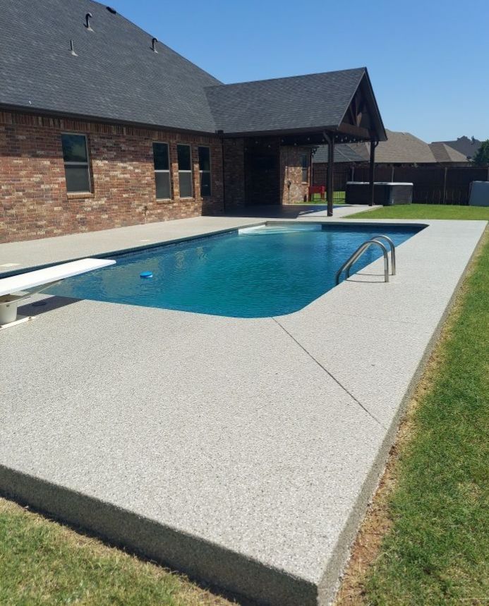 A large swimming pool in front of a brick house