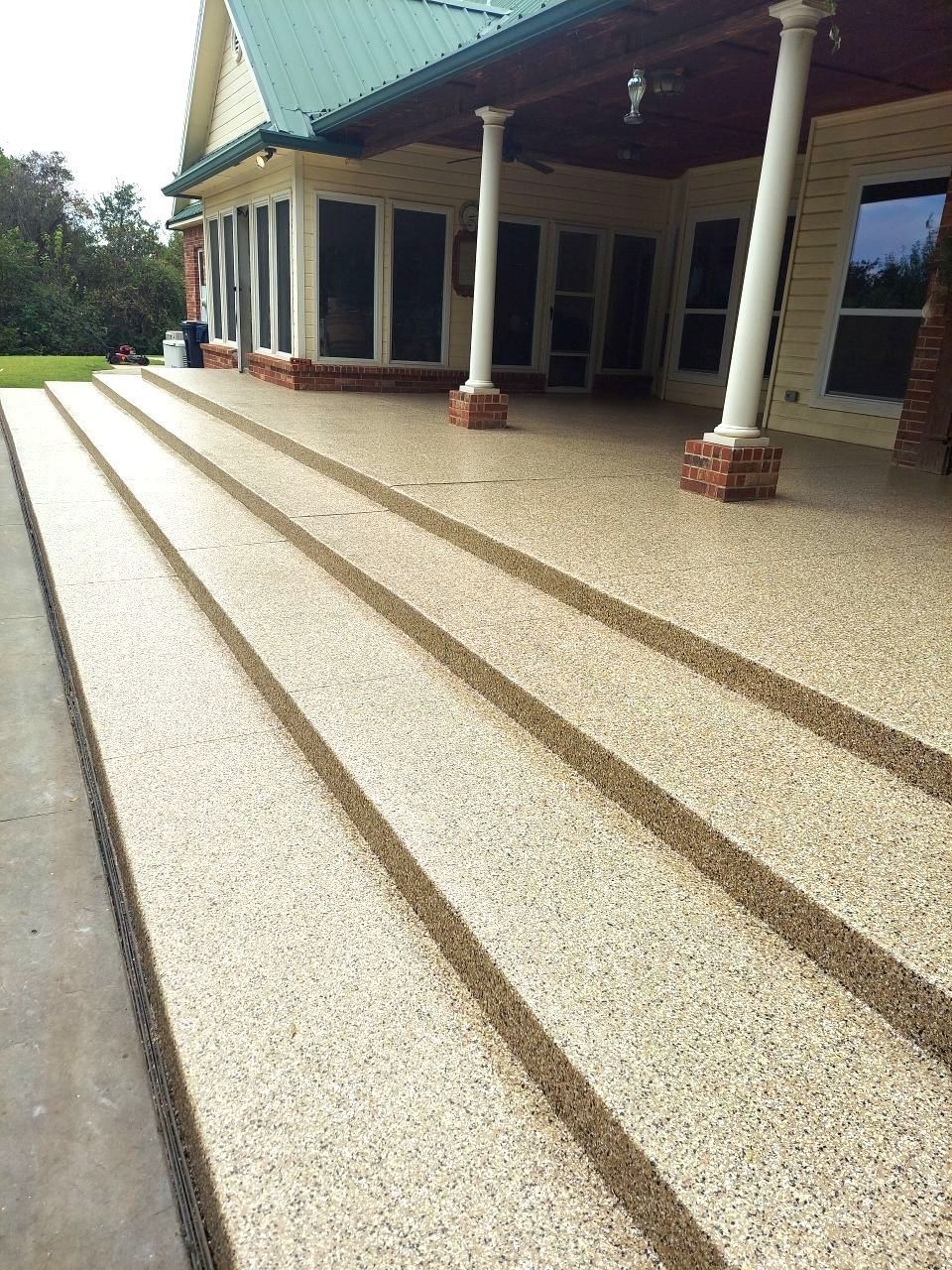 A patio with steps leading up to a house with a green roof