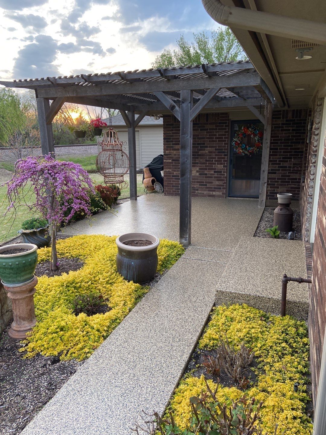 A walkway leading to a house with a pergola and potted plants