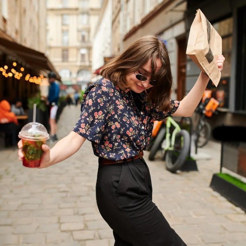 A woman is holding a cup of coffee and a newspaper.