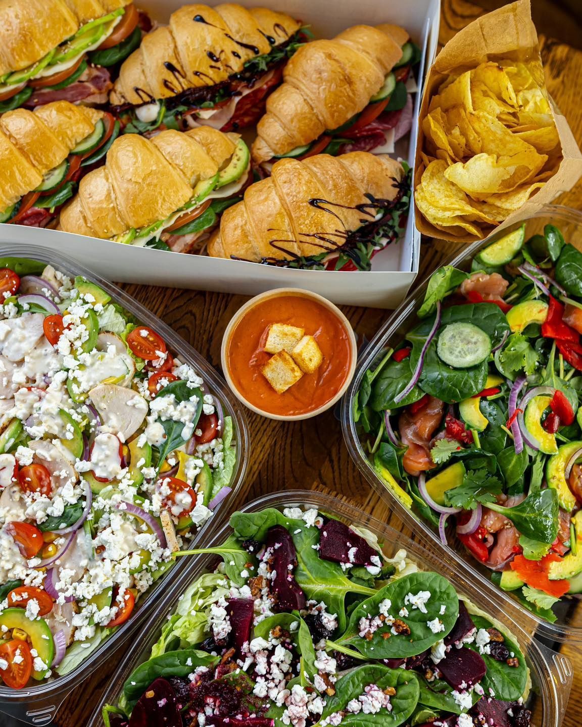 A table topped with a variety of salads and sandwiches.