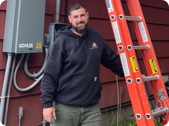 Electrician in orange and black gloves, wiring a light switch in a wall. Tools and blueprints are nearby.