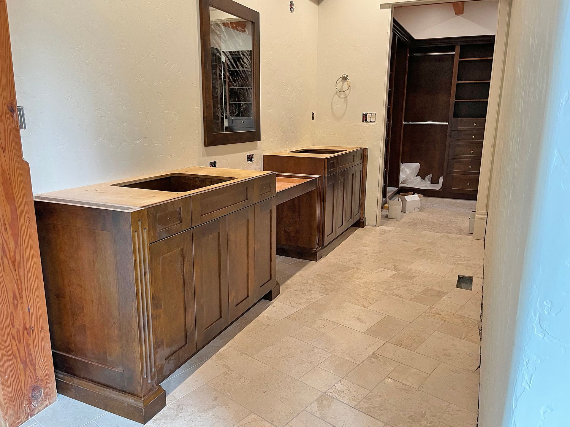 Long tiled hallway with wooden cabinets and a mirror on the left, leading to open shelving at the end.