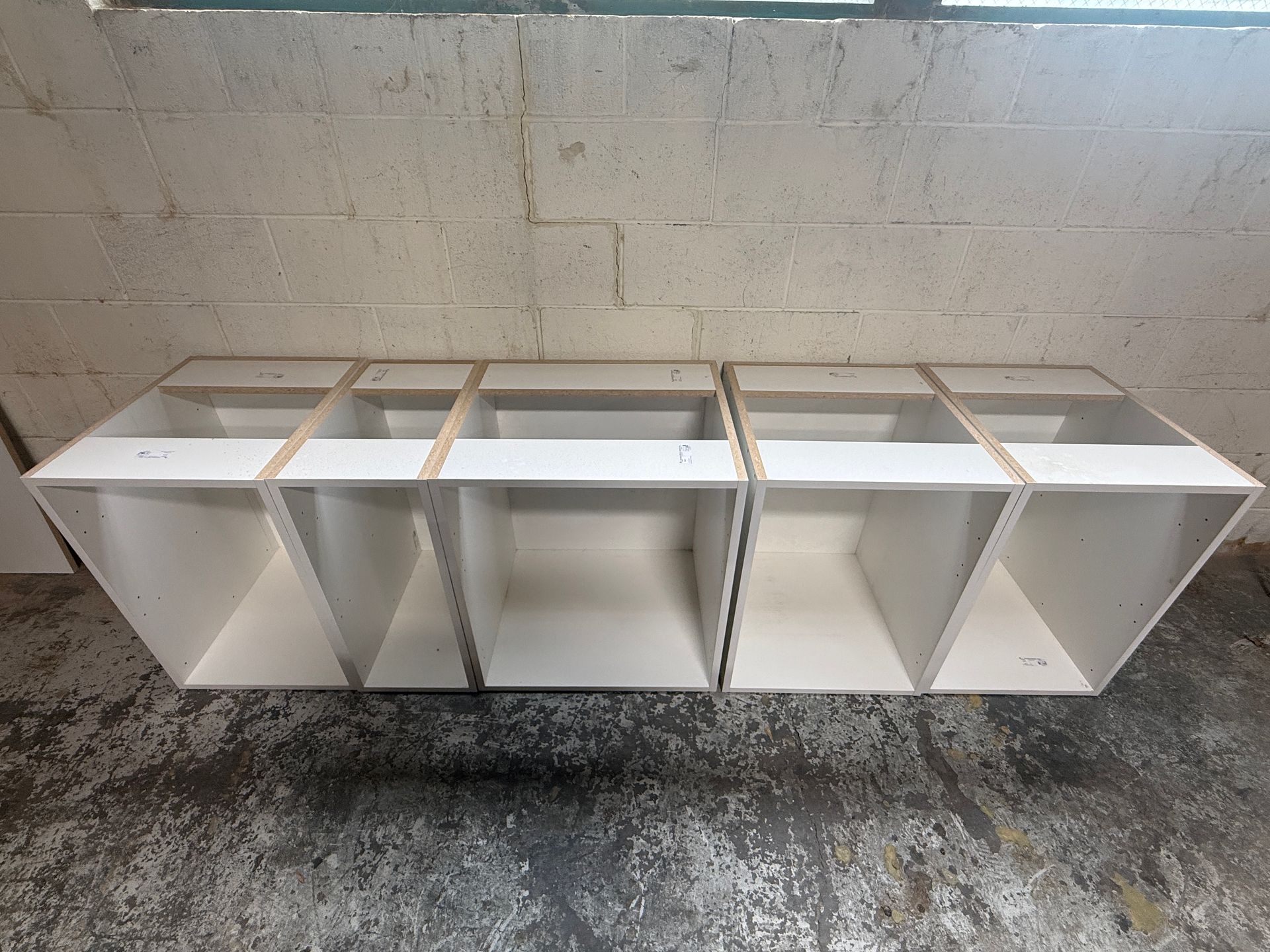 White wall-mounted shelving unit with open compartments in a tiled room.