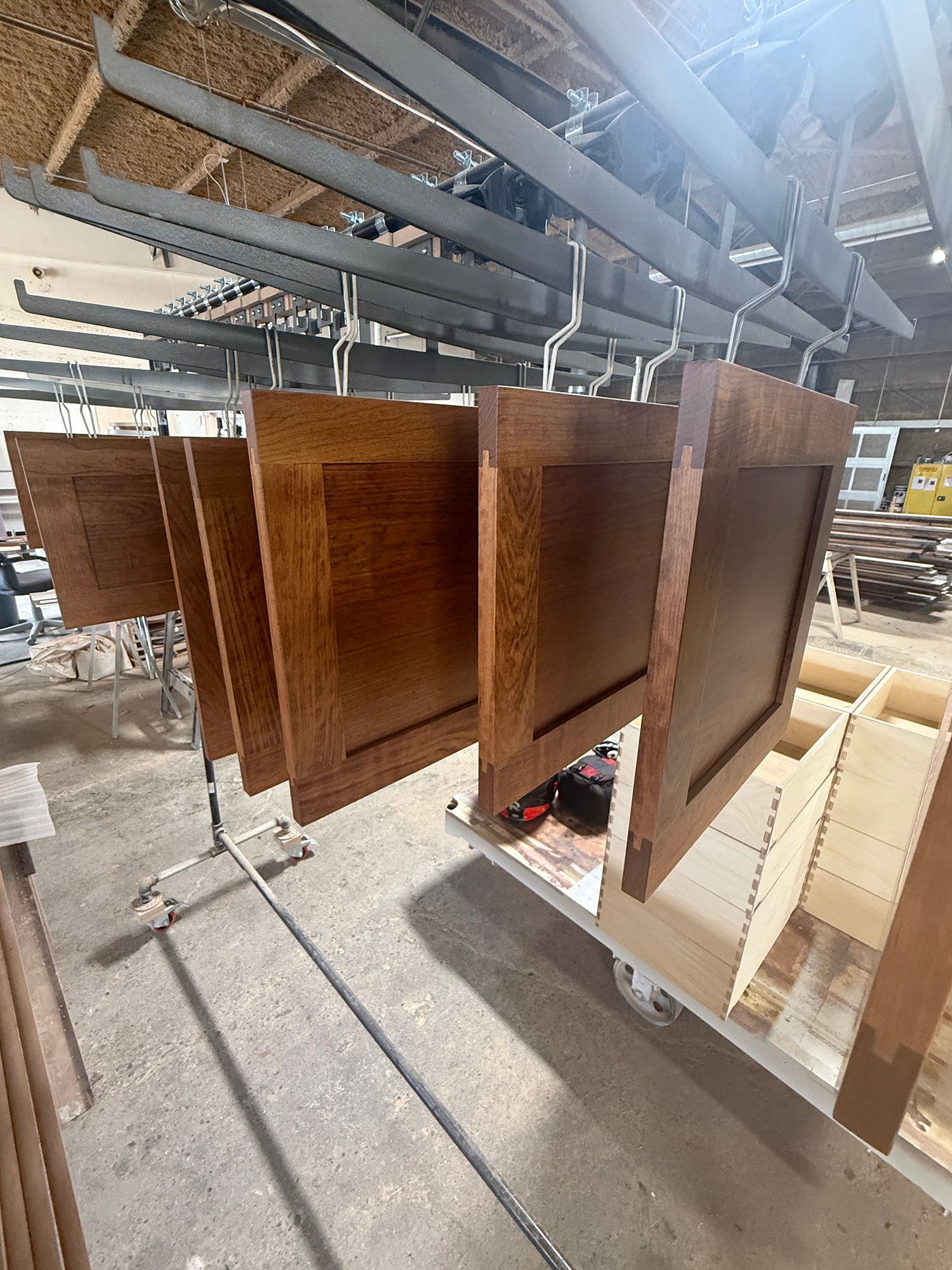 Wooden boards hanging in an industrial workshop, with stacks of lumber below.