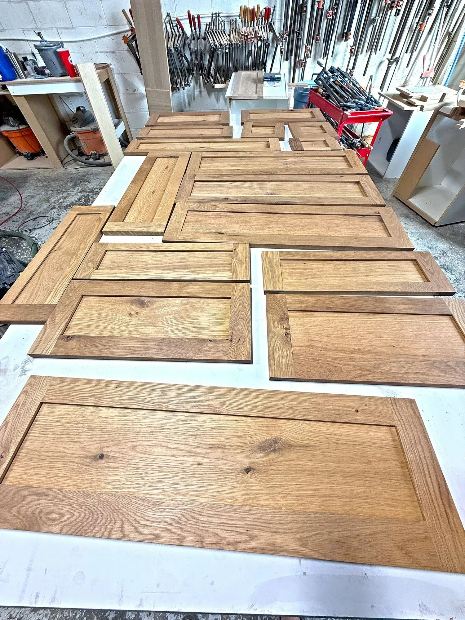 Wooden door panels laid out in a workshop, with unfinished frames and tools in the background.