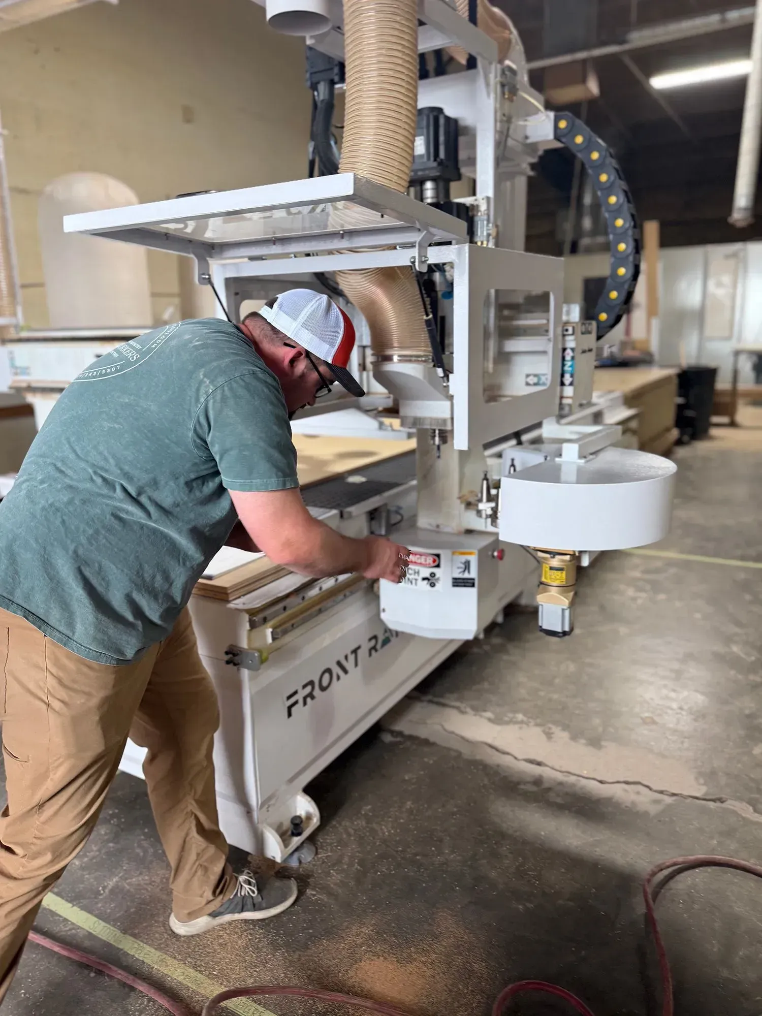 Worker operating a front-end loader in a warehouse, loading material into a machine.