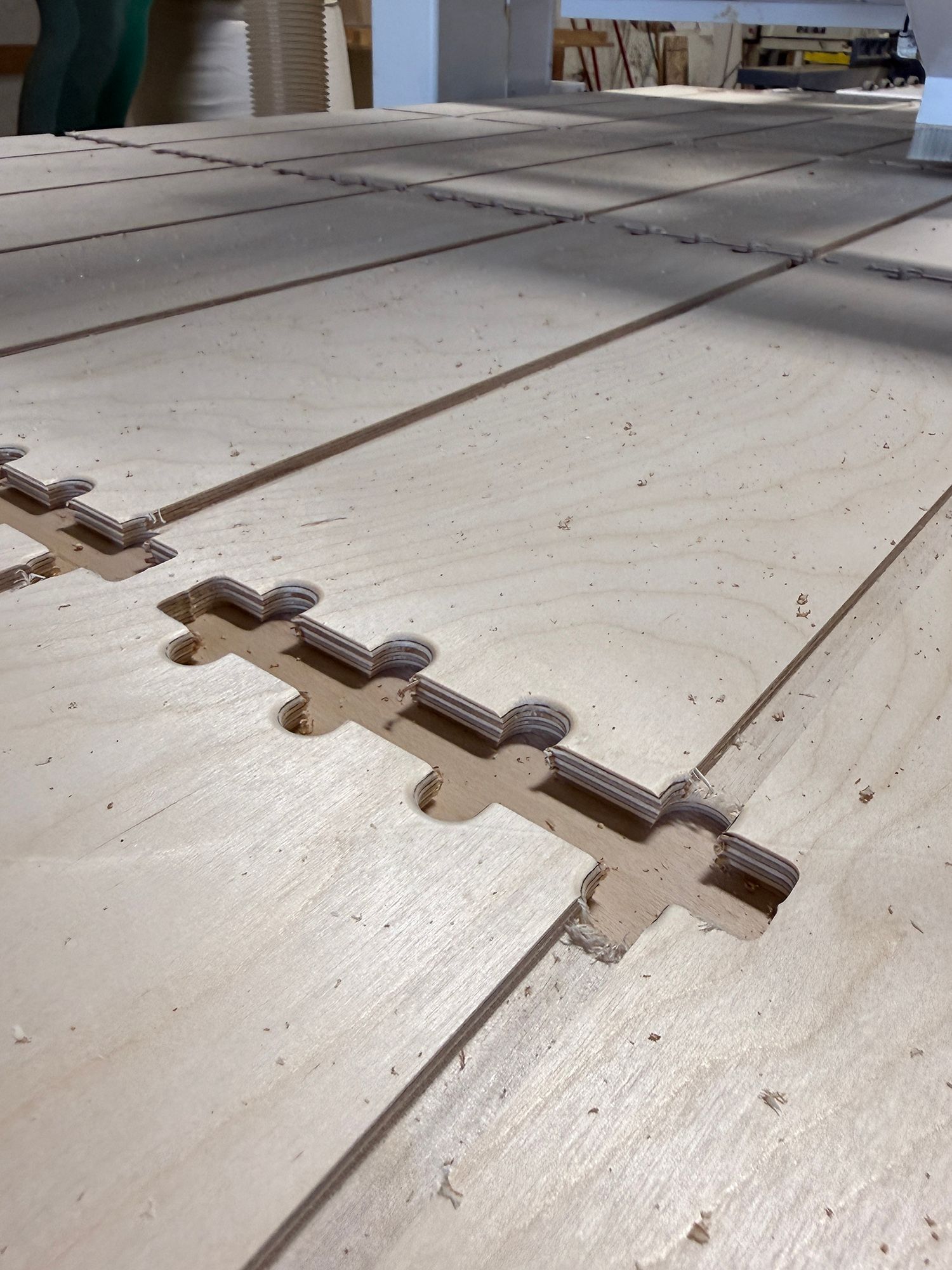 Interlocking beige foam floor tiles with puzzle edges laid out in a workshop-like space