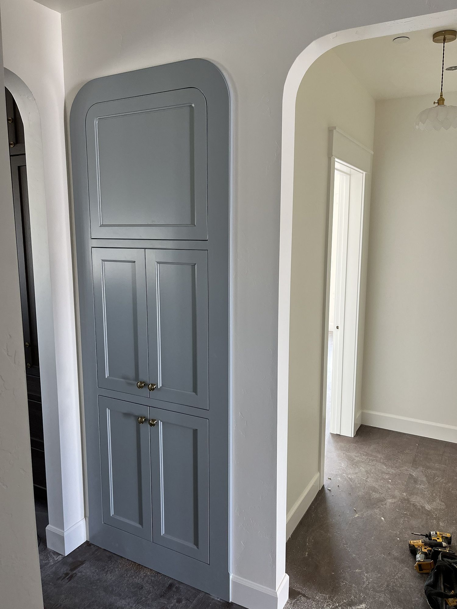 Gray built-in cabinet or closet doors in a narrow hallway beside an open doorway.