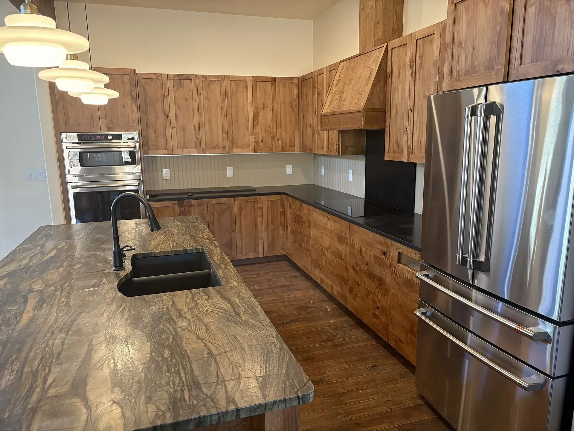 Modern kitchen with wood cabinets, stainless steel appliances, and a large stone island countertop.
