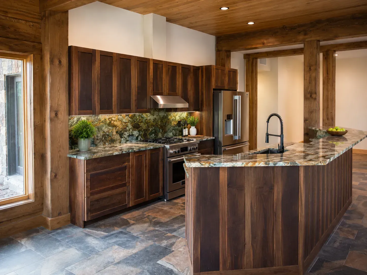 Modern kitchen with dark wood cabinets, stone countertops, and a curved island under warm recessed lighting.