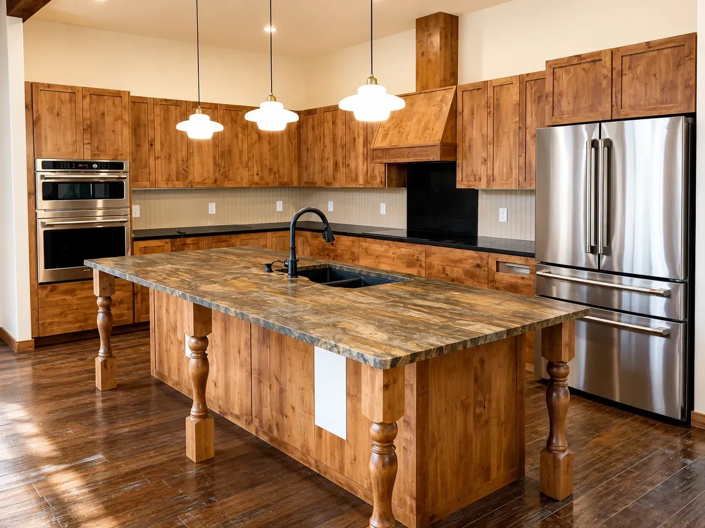 Modern kitchen with granite island, wood cabinets, stainless steel appliances, and pendant lights.