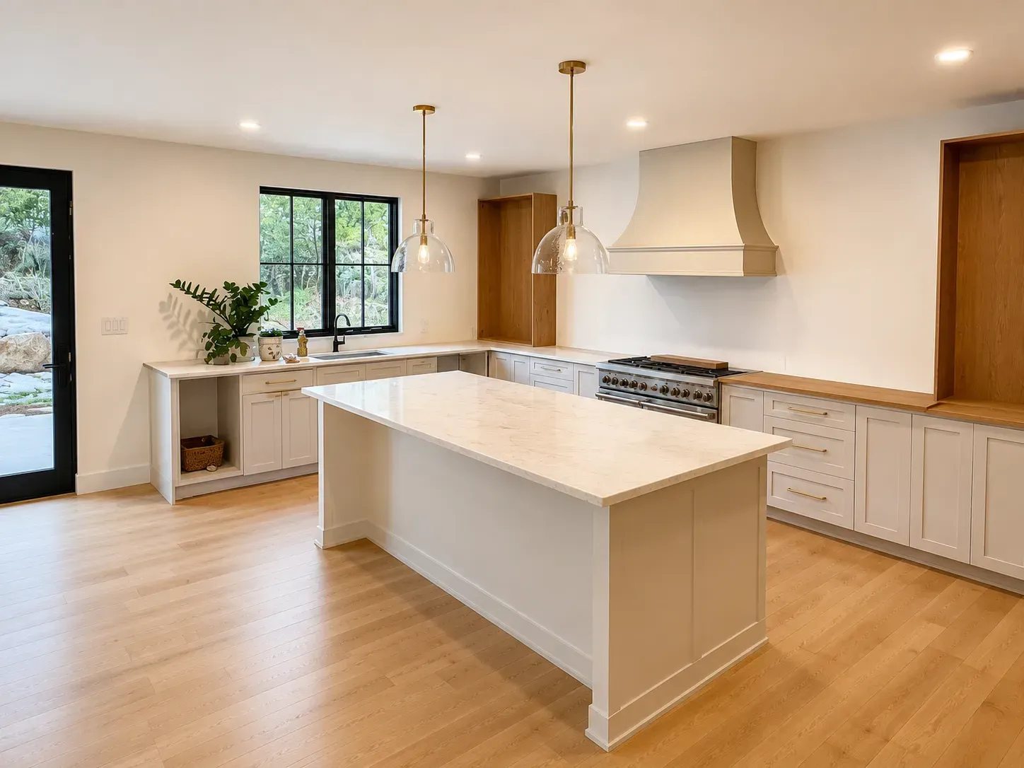 Bright modern kitchen with white island, wood floors, pendant lights, and large window.
