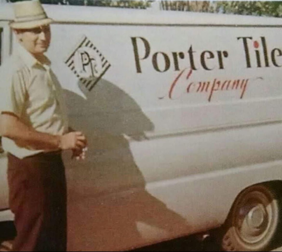 Man in fedora stands next to a Porter Tile Company van.