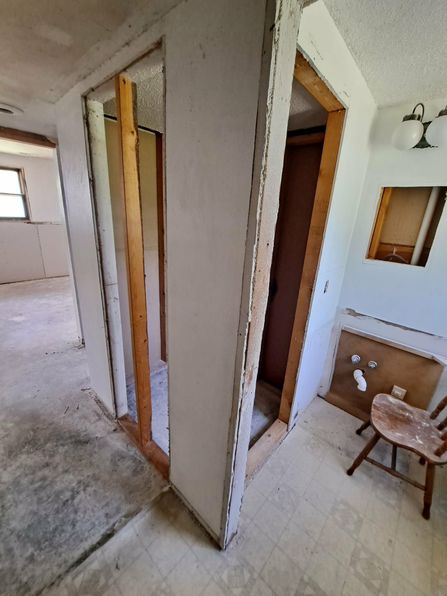 Interior renovation, open doorway frames with exposed studs, drywall, and partially removed wall.