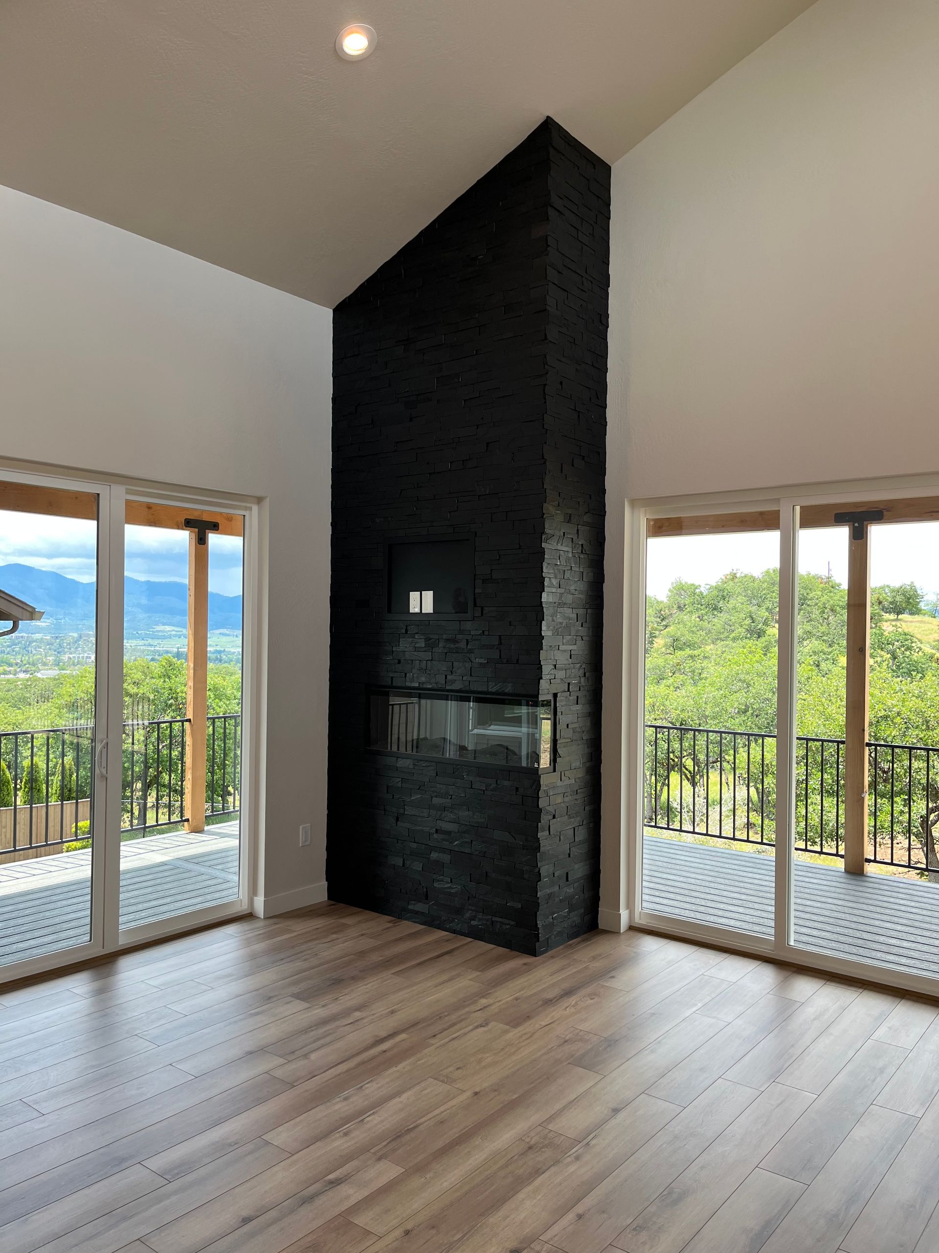 Empty modern living room with floor-to-ceiling windows and a black tiled fireplace wall