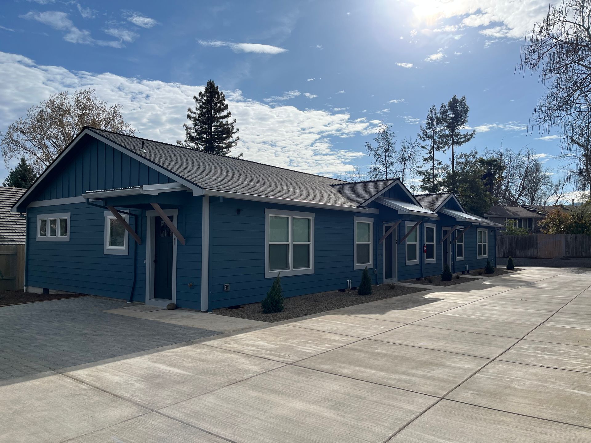 Blue single-story building with a metal roof and concrete courtyard under a bright sky
