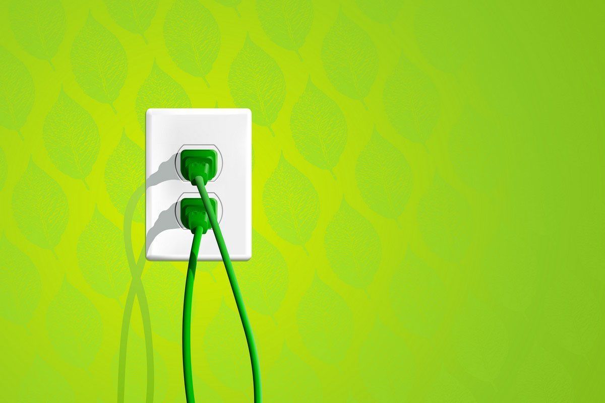 Green electrical outlet with green cords plugged in on a bright green wall.