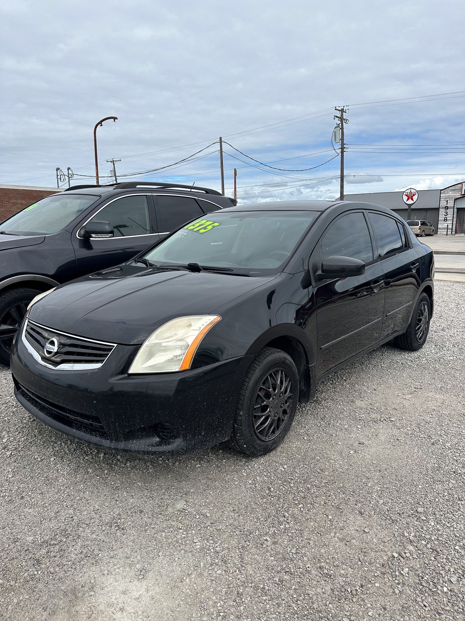 Black Nissan Sentra parked on gravel.