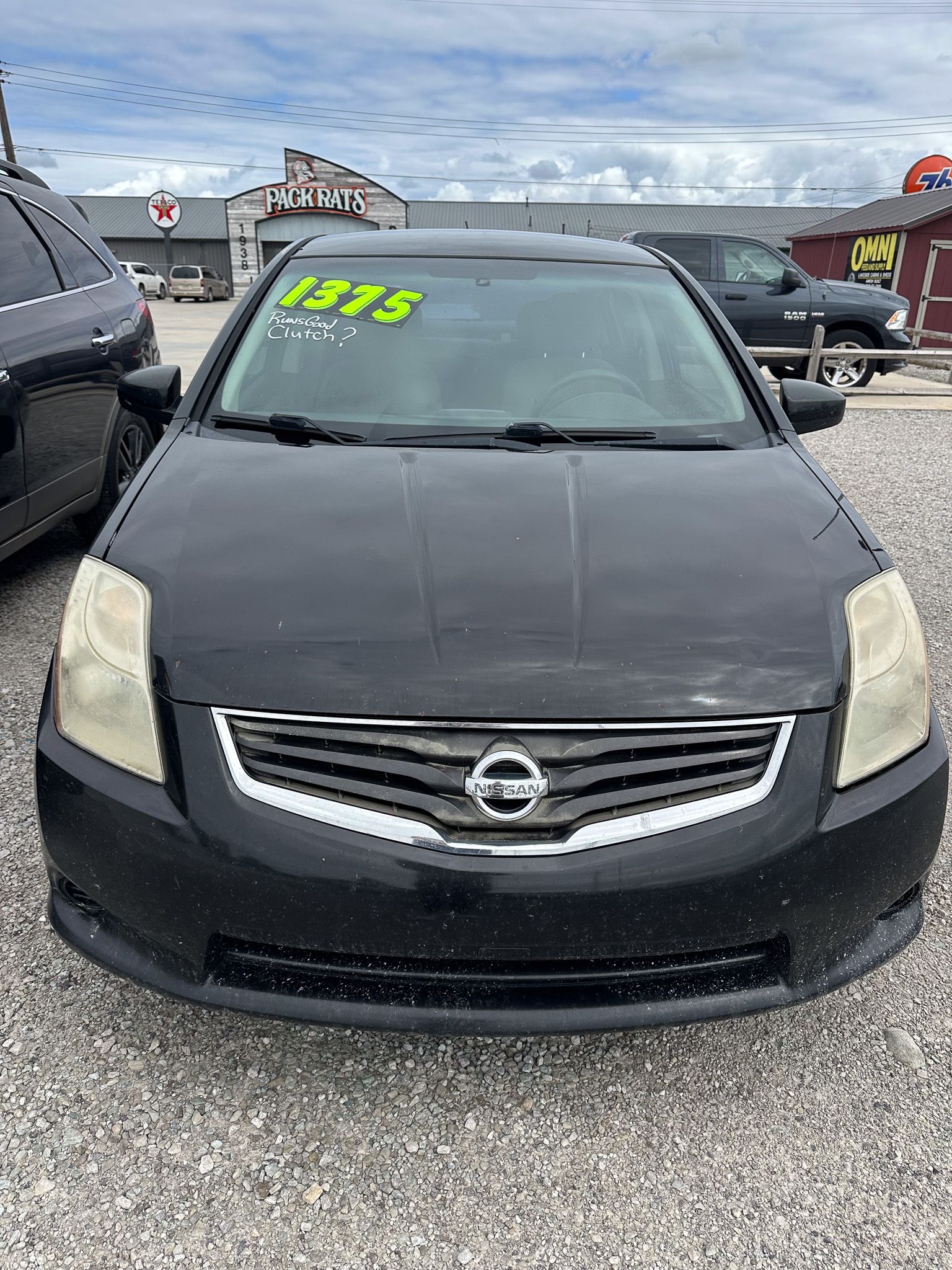 Black Nissan car in front of a dealership.