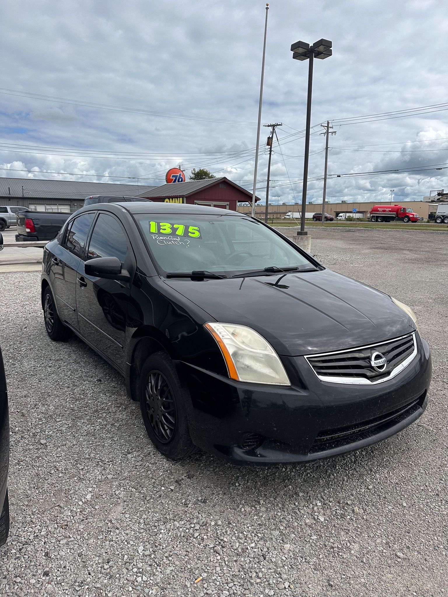 Black Nissan Sentra on a gravel lot.