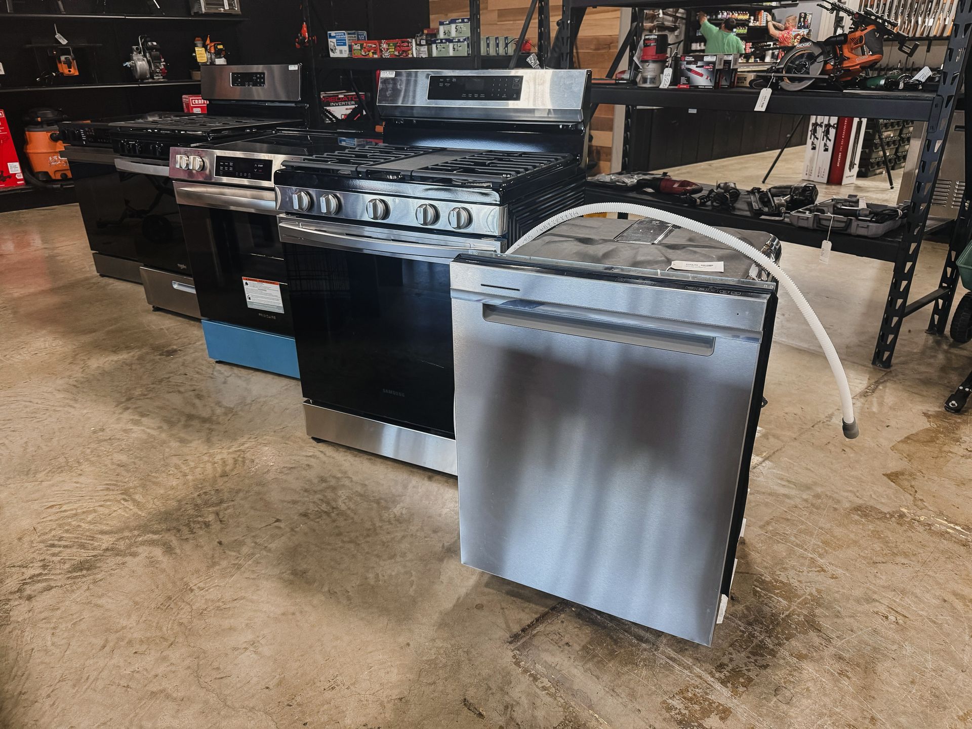 A stainless steel dishwasher is sitting next to a stove in a store.