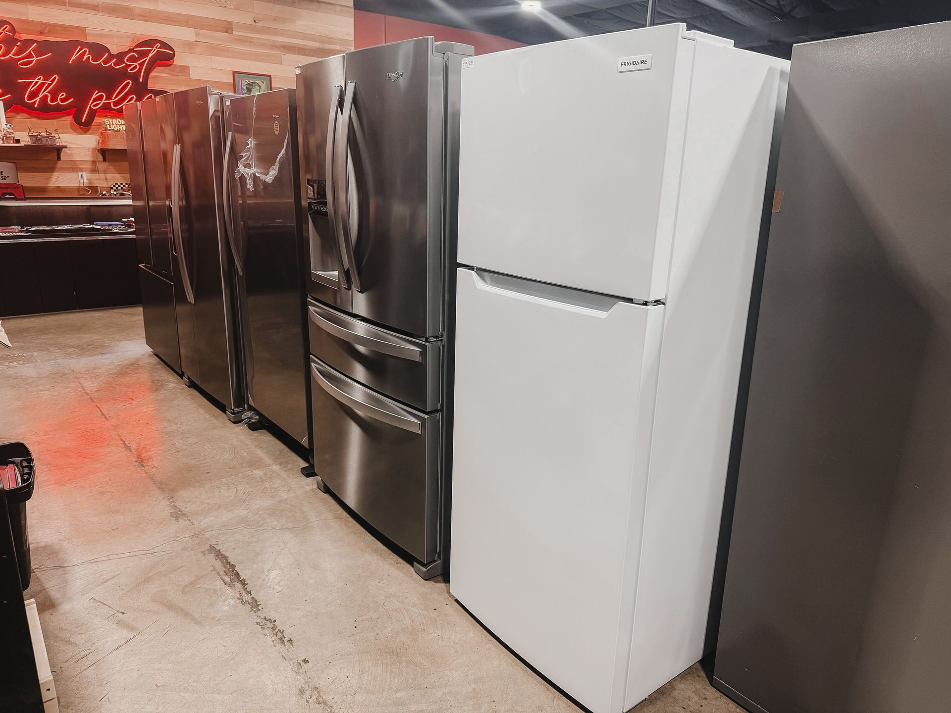 A row of refrigerators are lined up in a store.