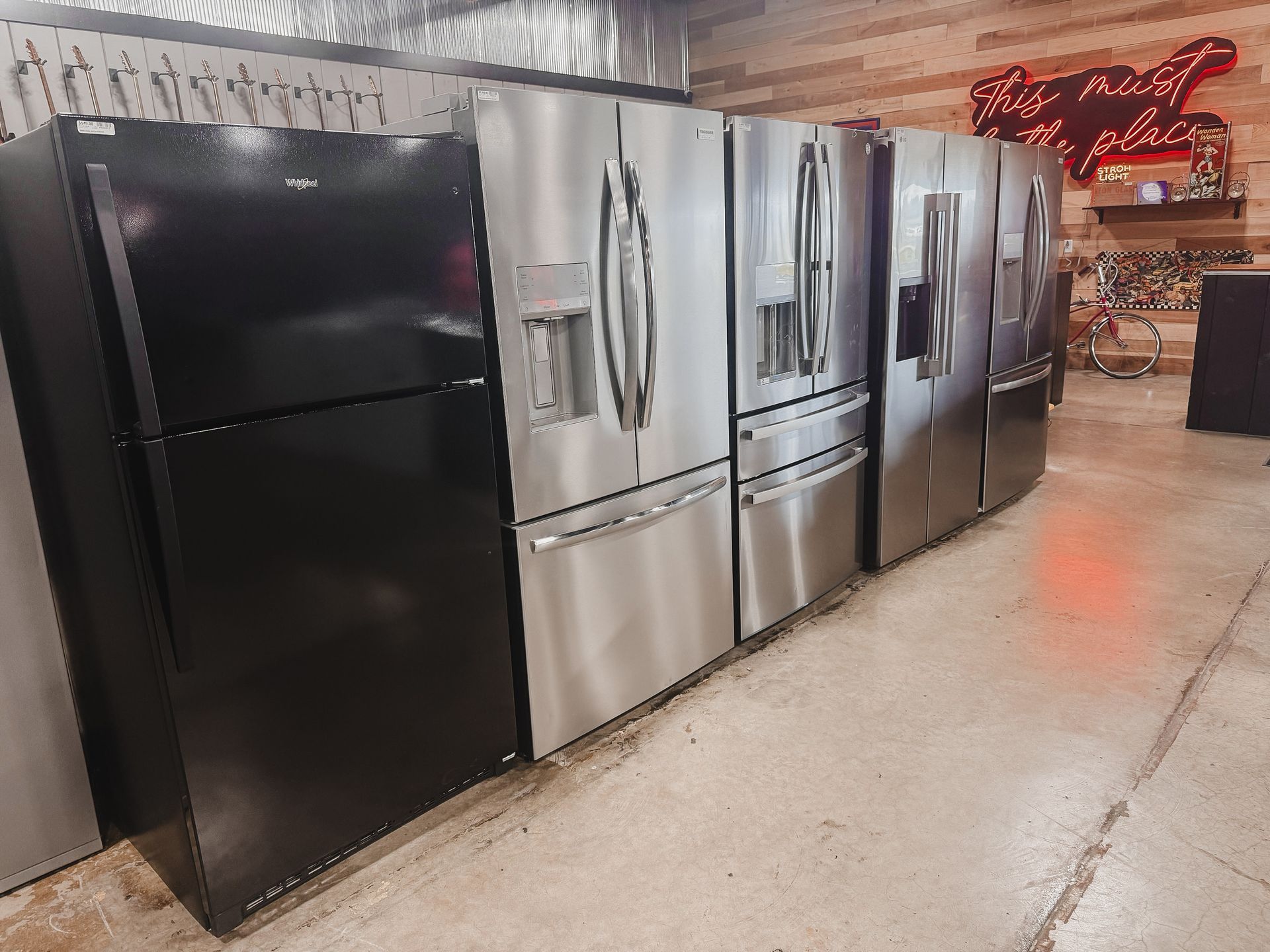 A row of refrigerators are lined up in a store.