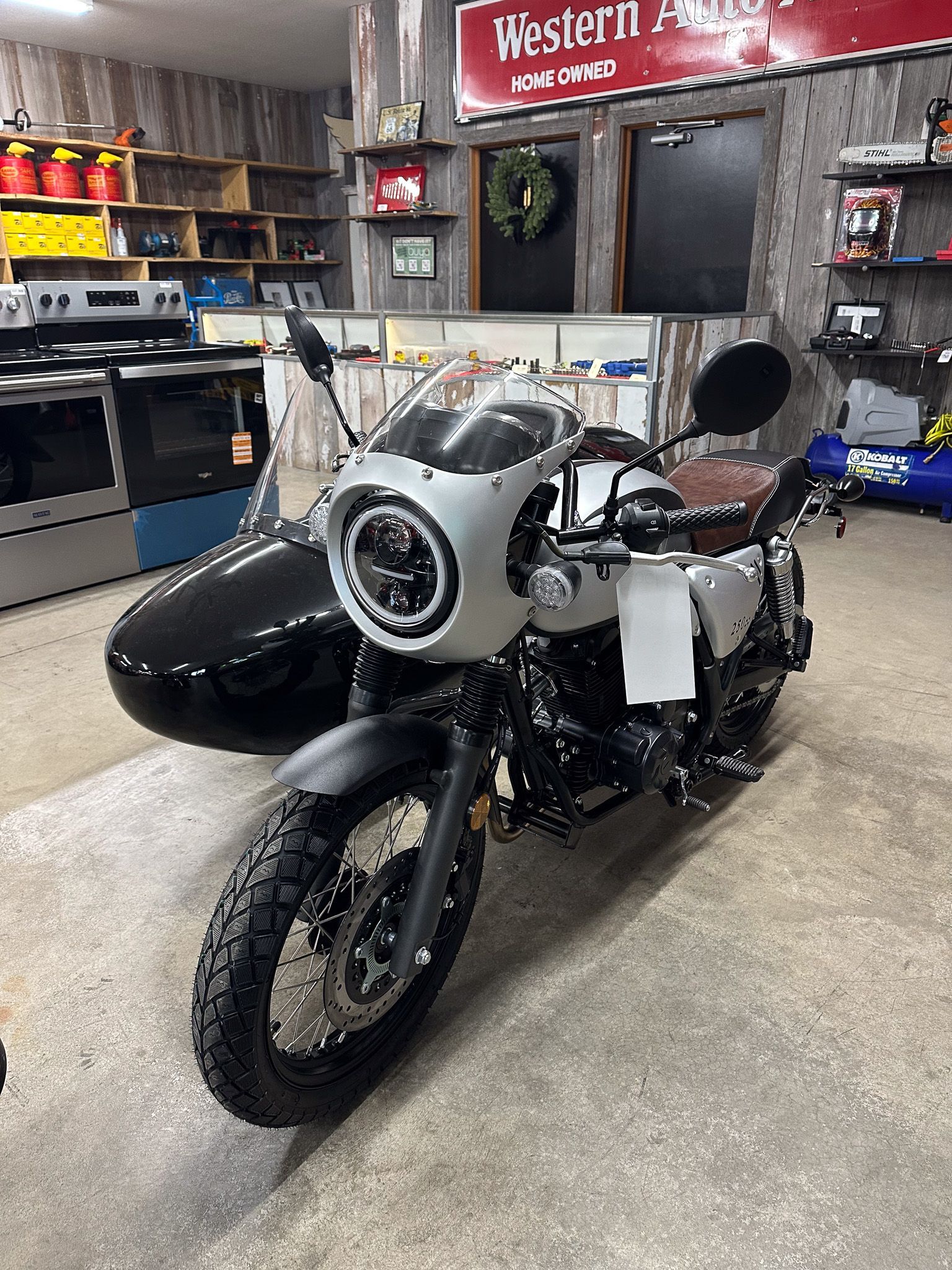 Motorcycle with a sidecar in a store with appliances and signs.