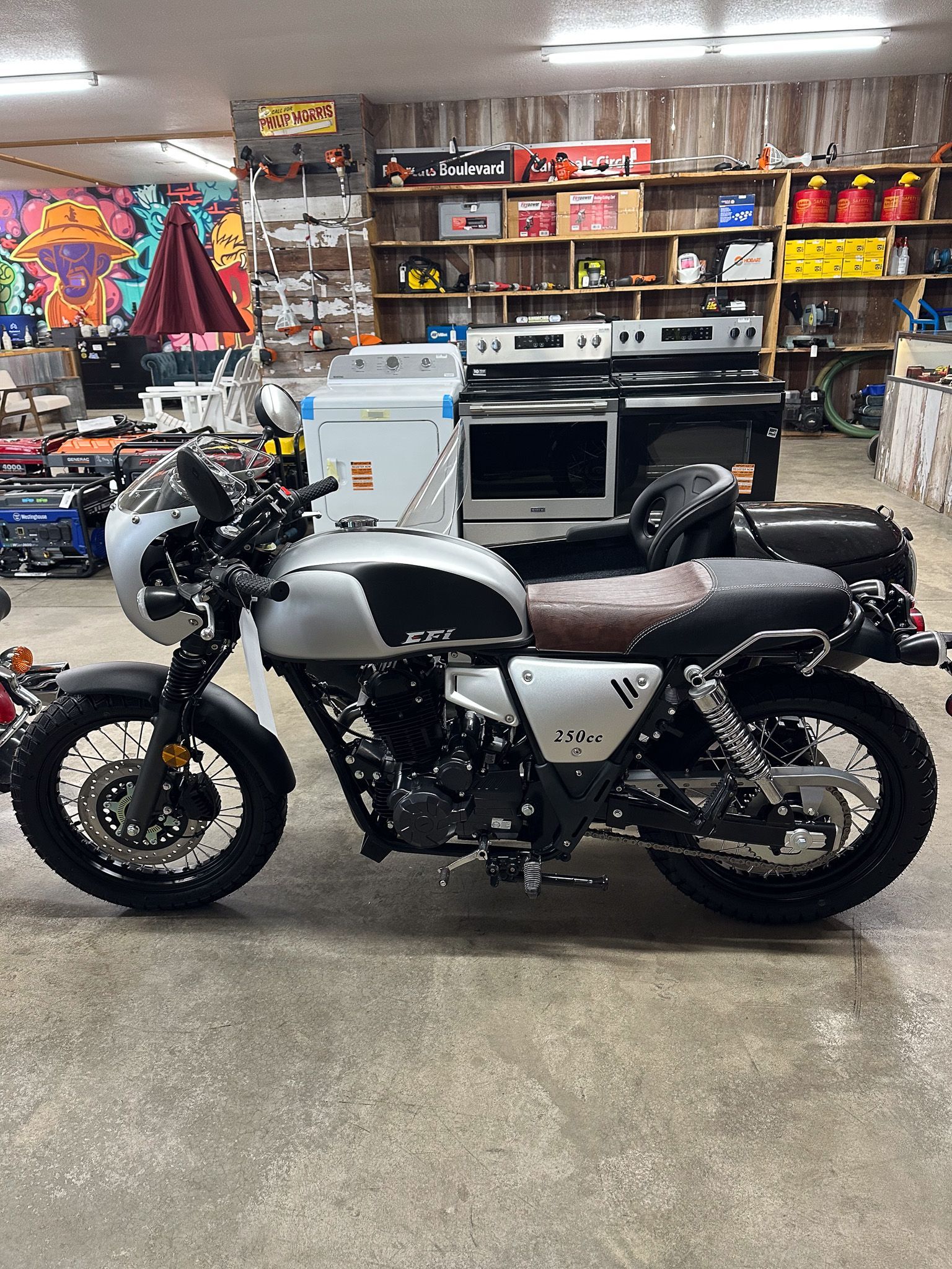 Silver and black motorcycle with brown seat, parked indoors in a store.
