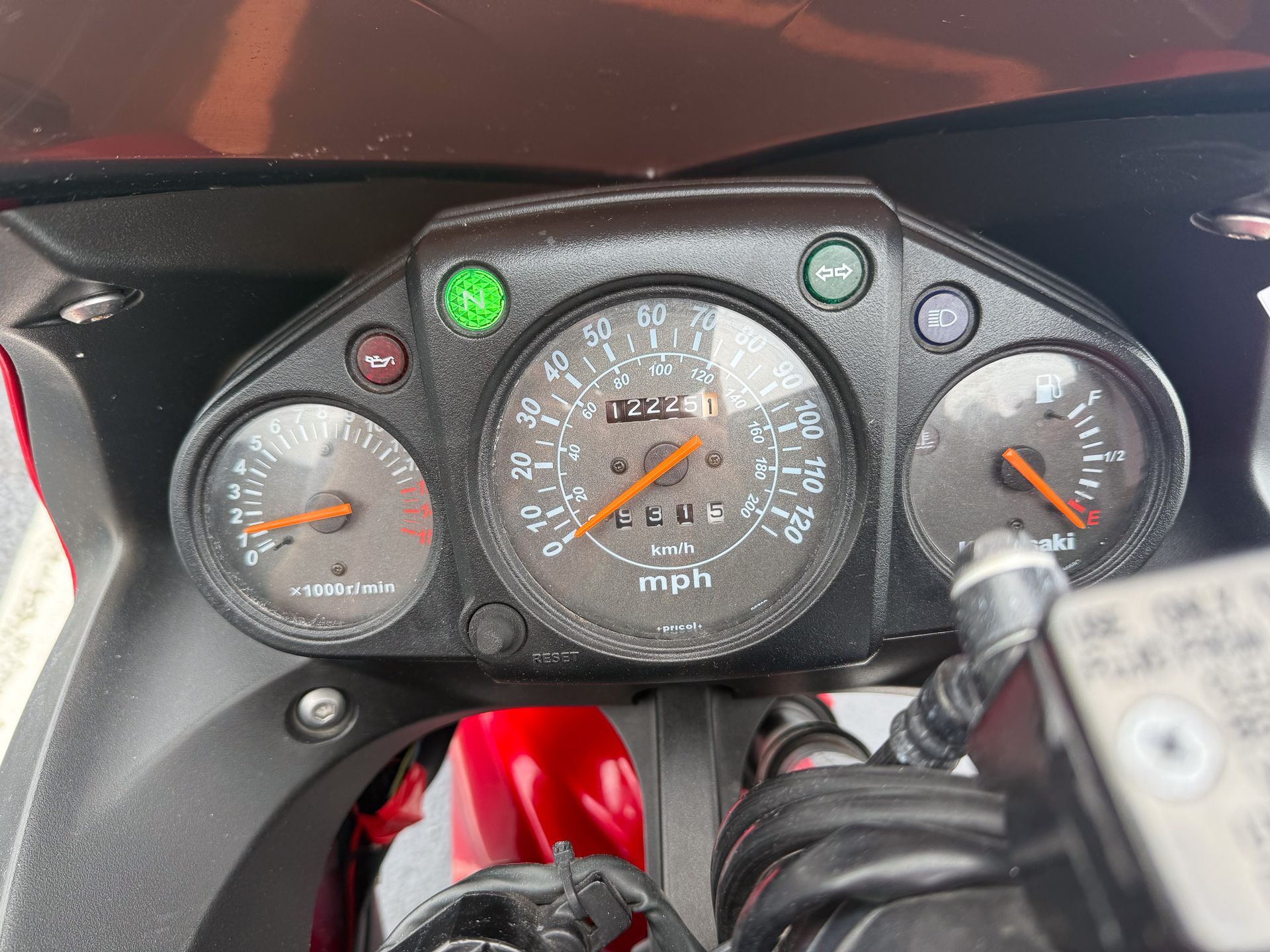Motorcycle dashboard with gauges, including speedometer at 42 MPH, indicator lights, and fuel gauge. Black and red.