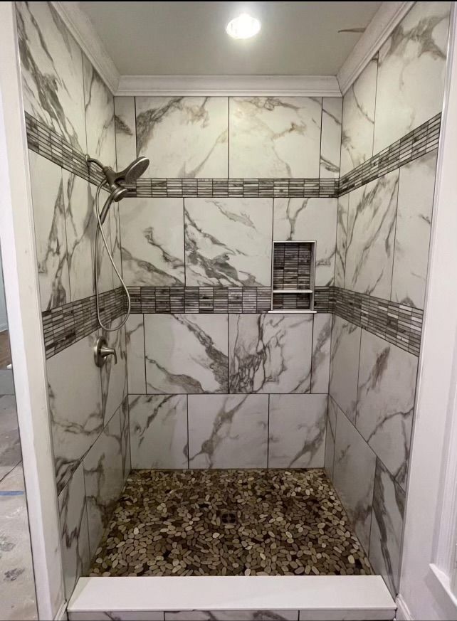 A bathroom with marble tiles and a walk in shower.