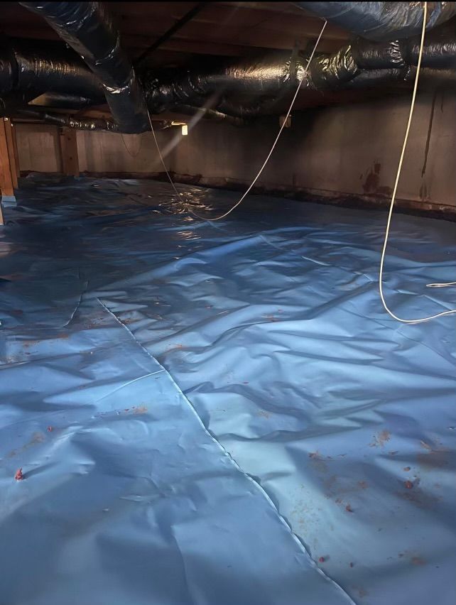 A blue tarp is covering the floor of a basement.