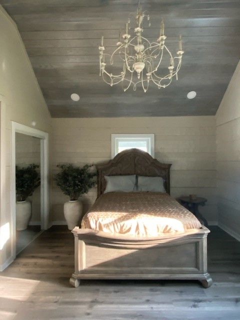 A bedroom with a bed and a chandelier hanging from the ceiling