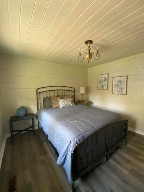 A bedroom with a bed, nightstand, and chandelier