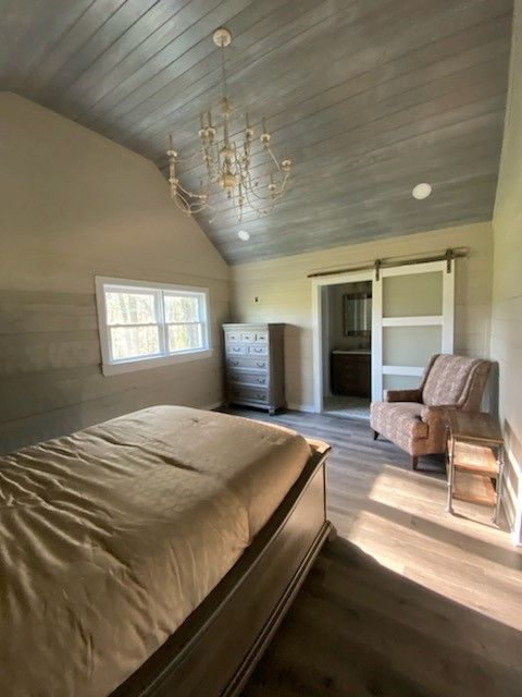A bedroom with a bed, chair and dresser