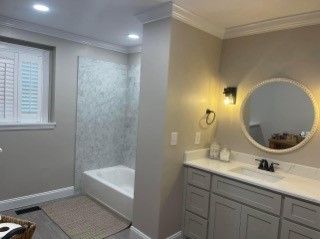 A bathroom with a sink, tub, mirror and window