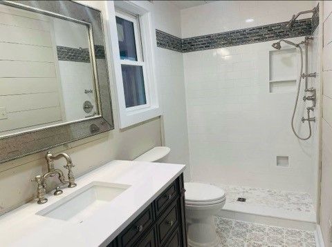 A bathroom with a toilet, sink, mirror and shower