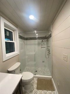 A bathroom with a toilet, sink, shower and window