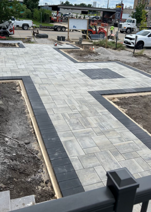 A brick walkway is being built in a parking lot