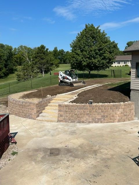 A bobcat is working on a brick wall in front of a house.