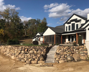 A large white house with a stone wall in front of it