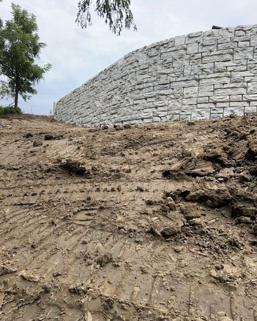 A large stone wall is being built on top of a dirt hill.